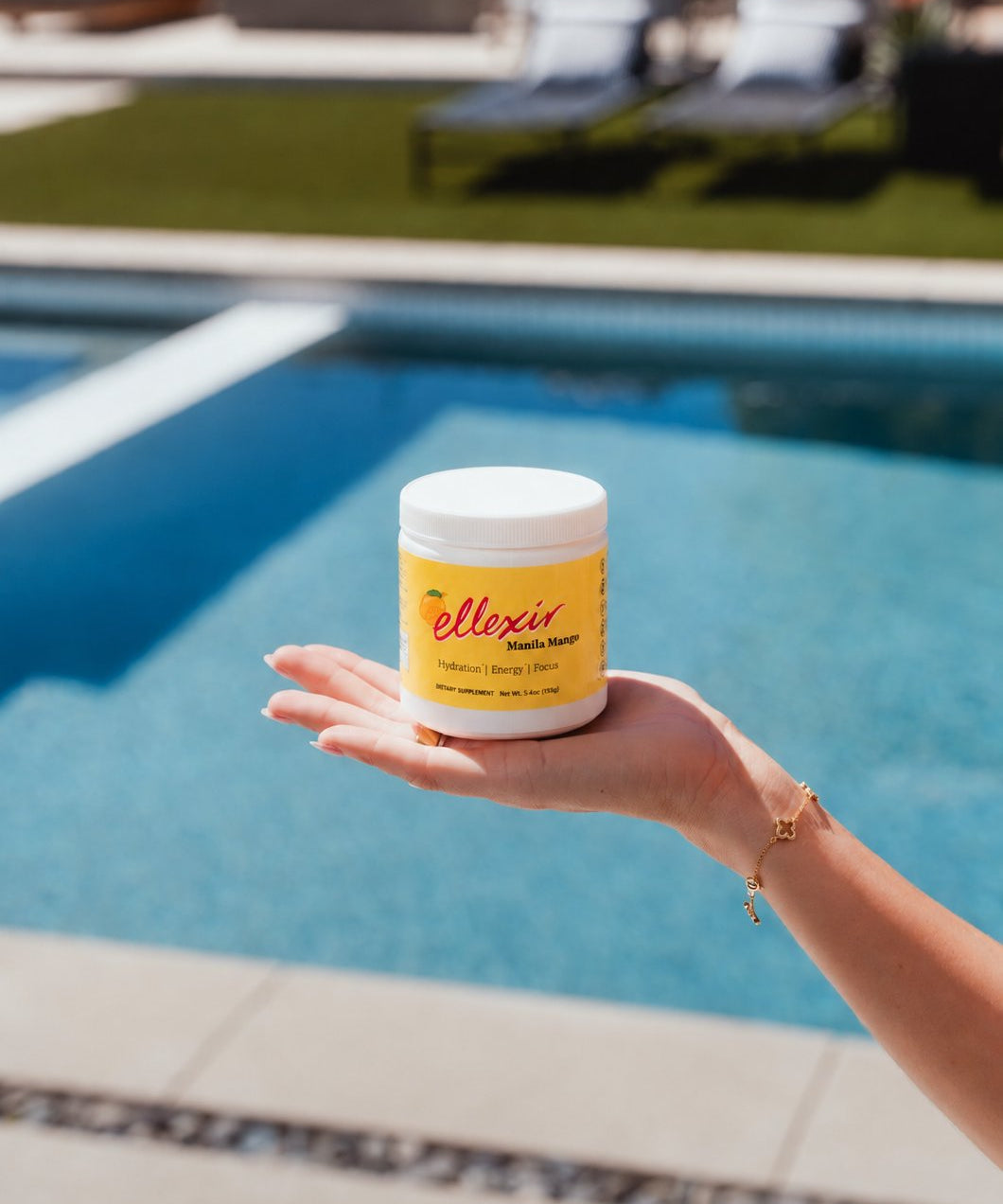 Ellexir Manila Mango Energy jar in hand by the pool