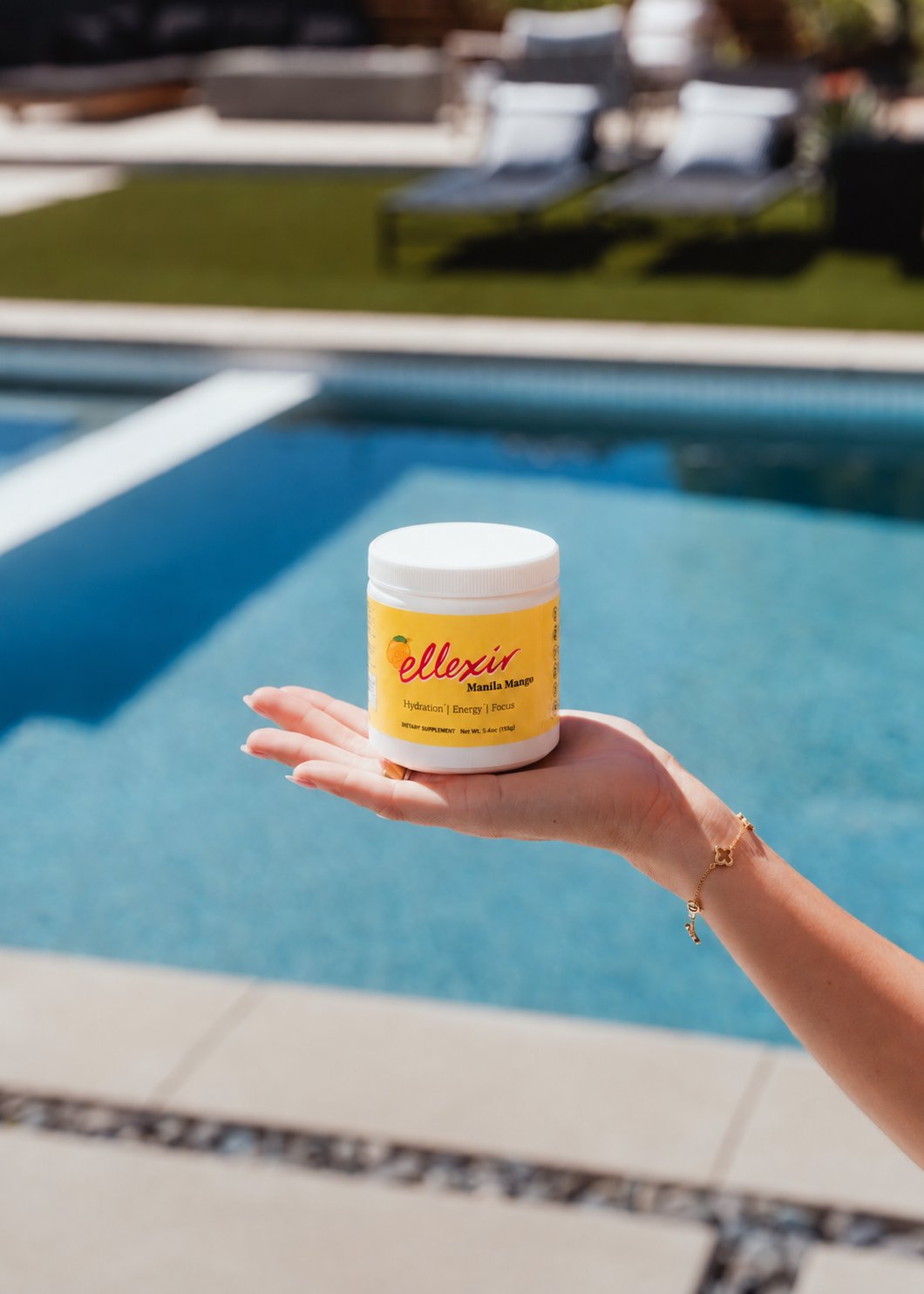 Ellexir Manila Mango Energy jar in hand by the pool